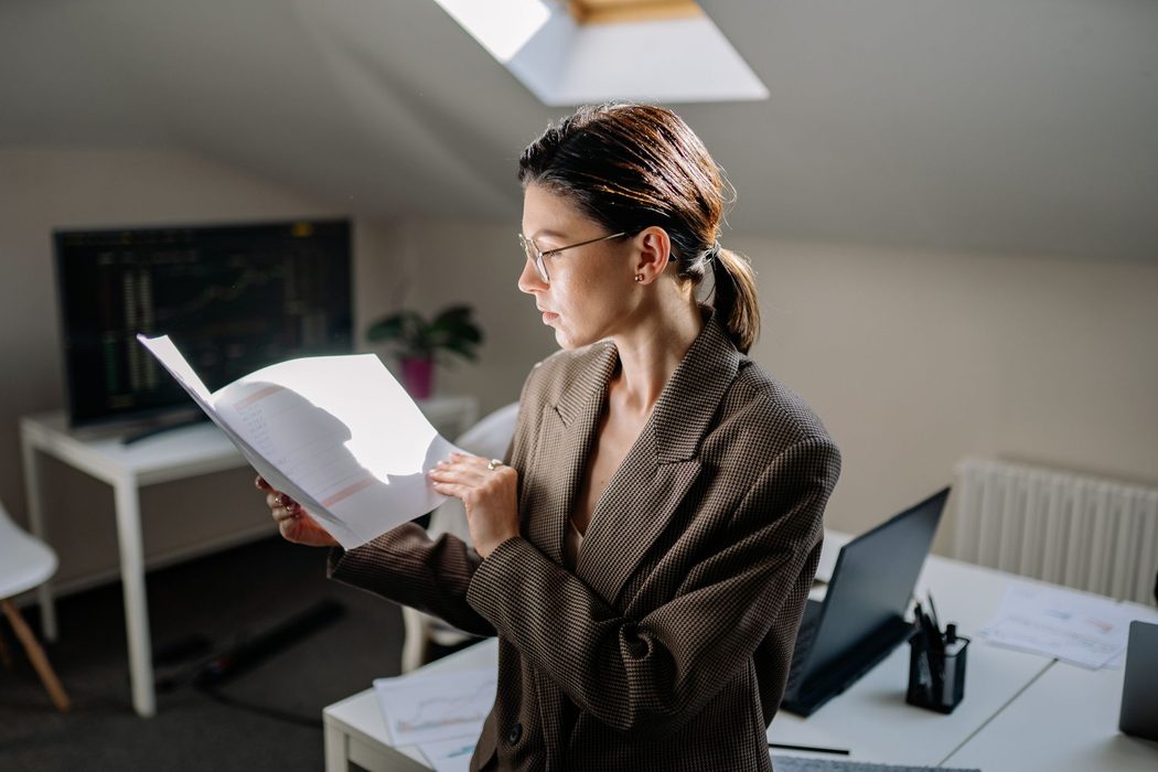 A person reviewing printed financial reports and data tables at a desk