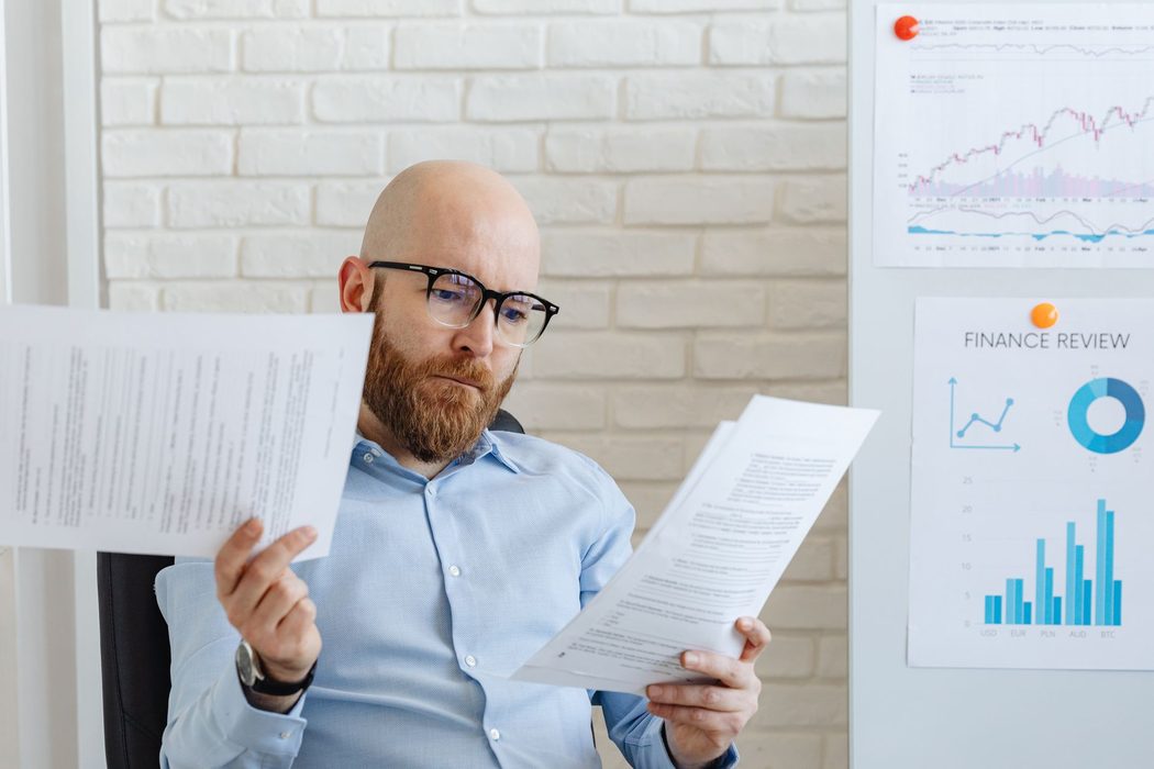 A reader studying printed charts and tables of economic data